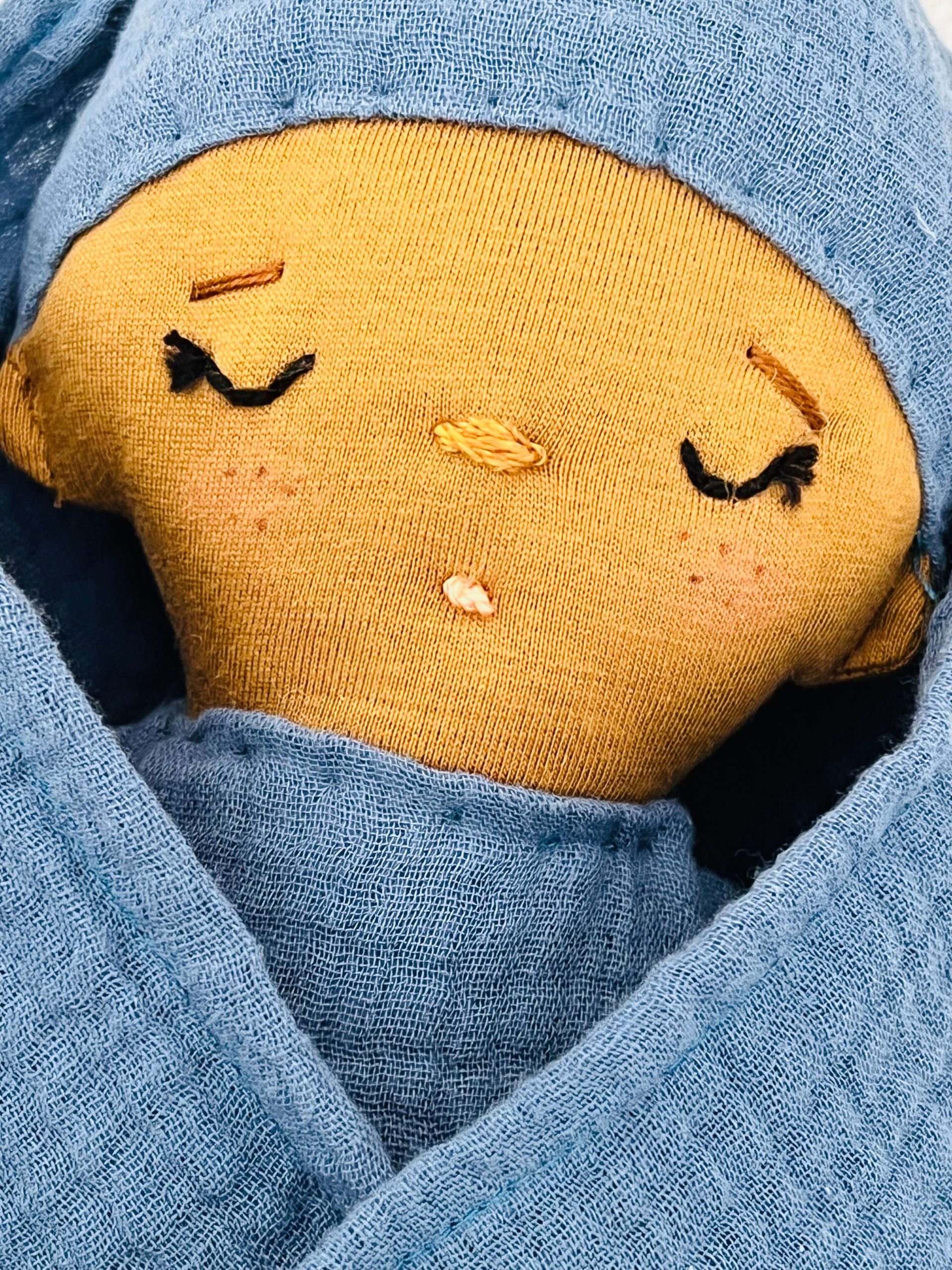 Muñeca de tela con cara bordada.